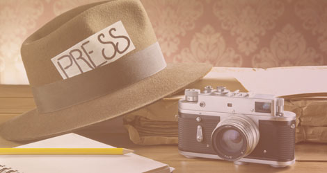 Die klassischen Gegenstände des Journalisten: Hut, Kamera und Notizblock