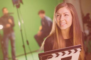 Studentin mit Filmklappe vor Green Screen