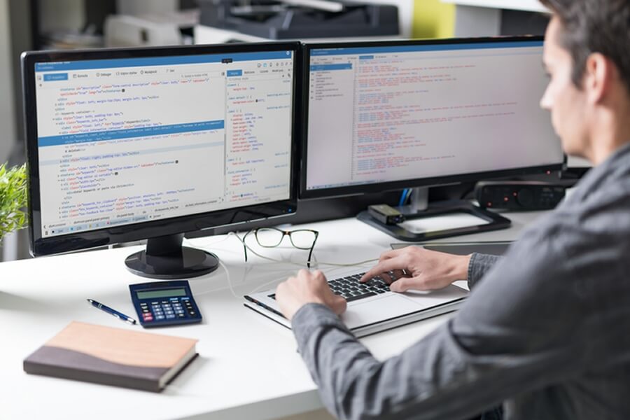 Ein Mediendesigner  untersucht den Quelltext einer Website.:  ... und setzen sie dann mit Code um.