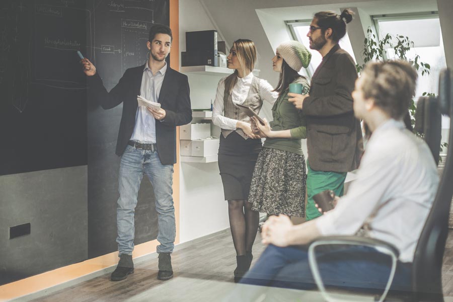 Medienmanagement-Student präsentiert etwas vor einer Gruppe an der Tafel :  Im Medienmanagement Studium beschäftigst du dich u.a. mit ...