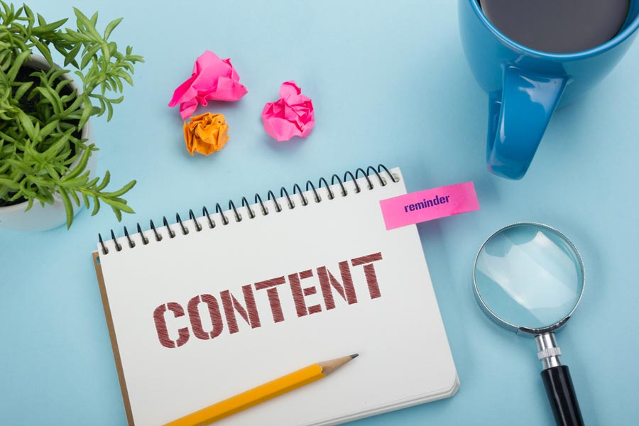 Notizbuch eines Medienmanagers, daneben eine Tasse Kaffee, eine Lupe und eine Tischpflanze:  ... sowie konkreten Marketingstrategien.