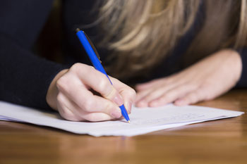 Nahaufnahme: Eine Frau schreibt auf ein Blatt Papier